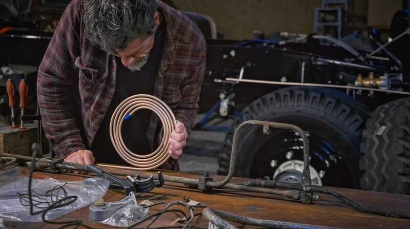 Man in workshop fabricating metal brake lines for a Bedford truck