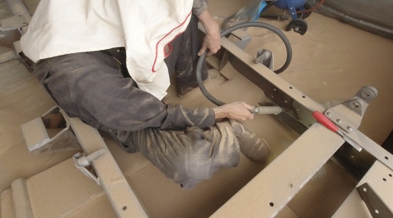 Man sandblasting a truck chassis frame