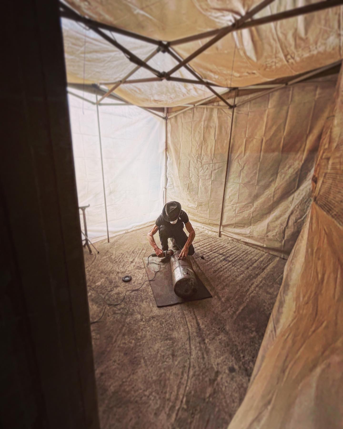Man in black inside a spray booth tent 