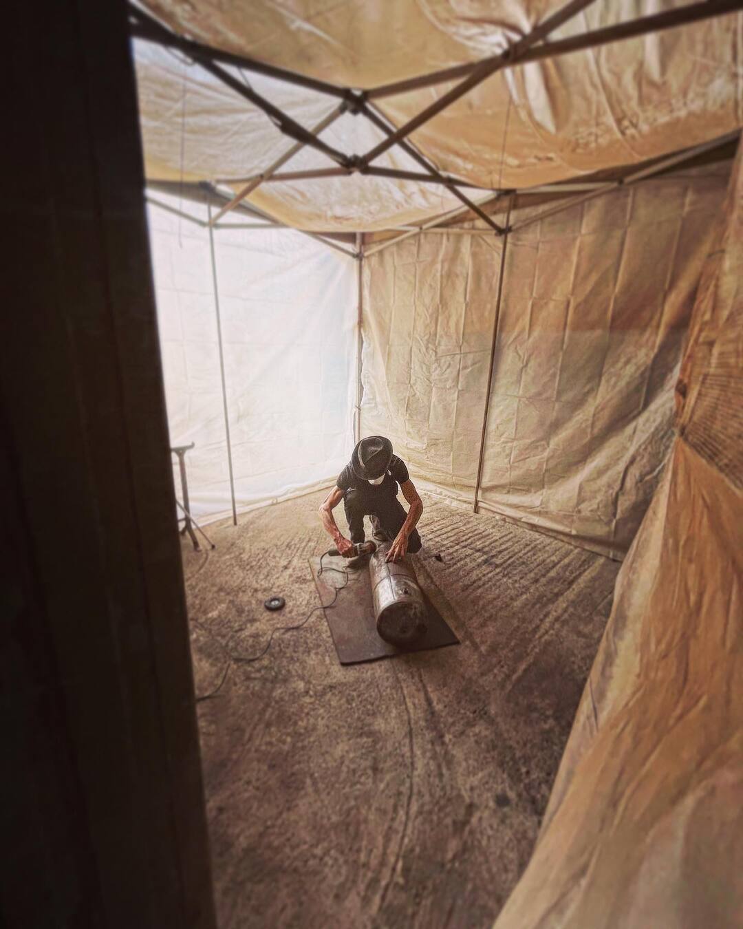 Man in black inside a spray booth tent 