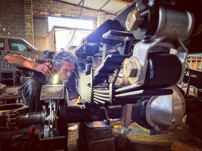 Man with torch inspecting the leaf springs on the back of a 1970s Bedford truck