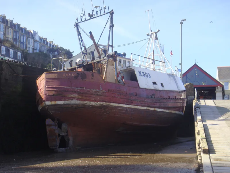 Large fishing trawler N303 moored against harbour wall at Ilfracombe in Devon at low tide