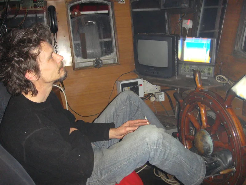 Man sitting at the wheel of a fishing trawler