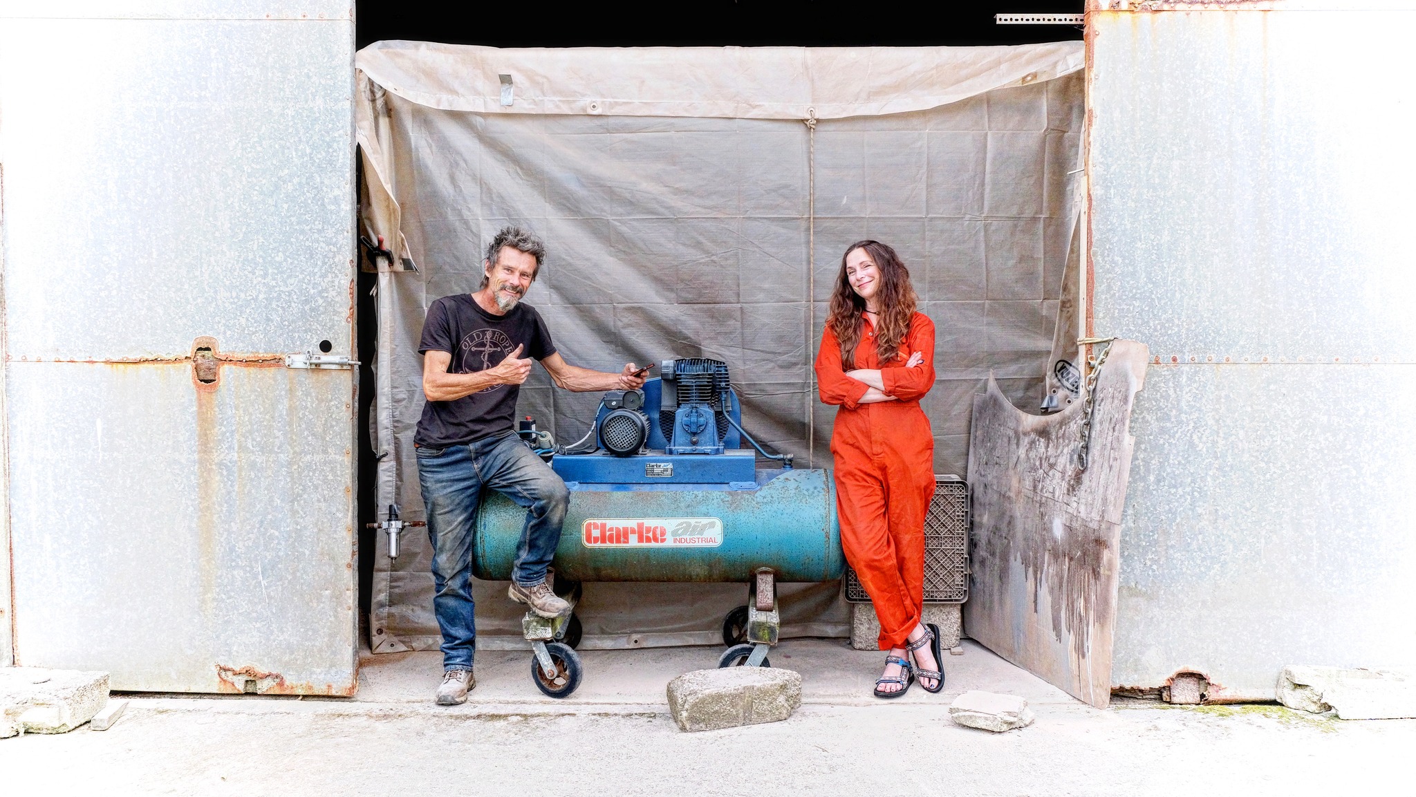 Man and a woman in orange overalls standing either side of a large compressor