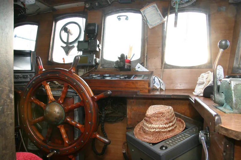 Inside the wheelhouse of a fishing trawler with a wooden ship’s wheel