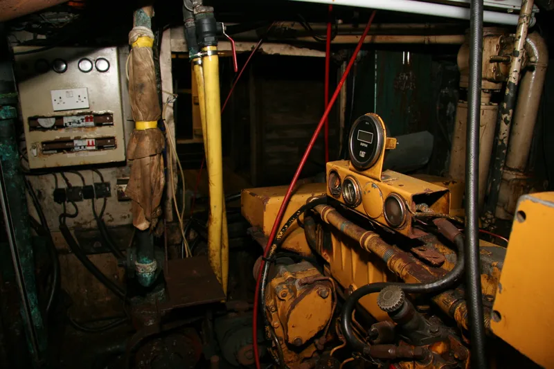 Engine room of a fishing trawler with a yellow Caterpillar engine