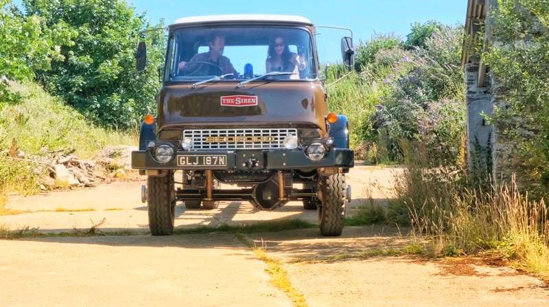 Classic Bedford truck freshly painted and restored being driven by a man and a woman on a sunny day